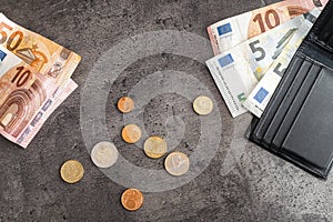 Close up of money banknotes, coins and black wallet. Euros on dark background photo