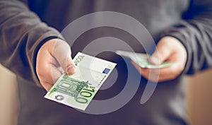 Close up money in mans hand. Man giving hundred euro. shallow depth of field.