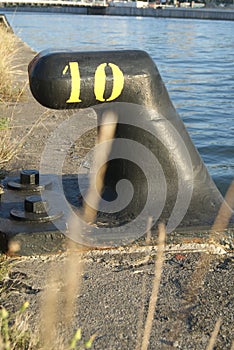 Close up of mooring noray on a dock with yellow number ten in iron. photo
