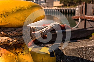 Close-up of a mooring rope with a knotted end tied around a cleat on a wooden pier