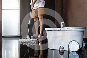 Close up mopping bucket with man mopping floor background