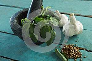 Mortar and pestle with herbs and spices on wooden table