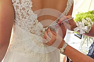 Close up of Hands Doing Final Buttoning of Bride& x27;s Wedding Dress