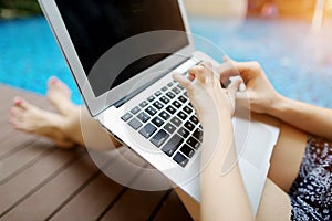 Close up mother and daughter hands pressing keyboard on laptop sunny day swimming pool