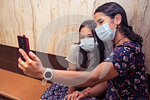 Close up mother and daughter taking a photo with the smart phone and wearing surgical mask. Indoor photography on the metro