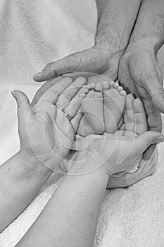 loving parents hands holding their baby's feet