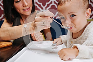 Close up of mother feeding her baby, sitting in a high chair