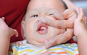 Close-up mother hands open baby mouth to examine first teeth. Infant primary tooth