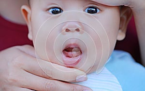 Close-up mother hands open baby mouth to examine first teeth. Infant primary tooth