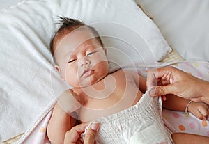 Close up of mother hands put on a baby diaper to her newborn