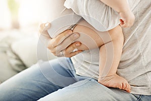 Close up of mother holding her newborn baby boy with hand. Little kid leg and big caring hand of mother.Family scene.