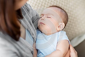 Close up of mother holding sleeping asian baby boy