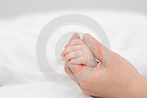 Close up mother holding tiny hand of little newborn baby boy girl, helping hands, bonding different generations. Happy