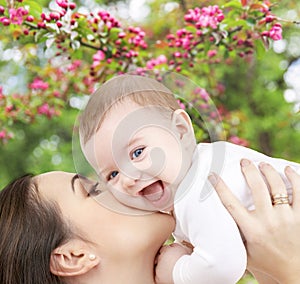 Close up of mother kissing baby over garden photo
