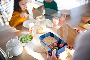 Close-up of mother preparing snack to lunch box in kitchen at home.