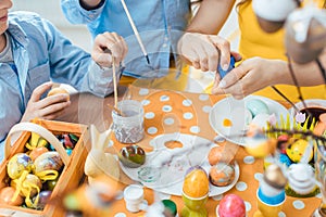 Close-up of mother, son, and a friend coloring eggs for Easter