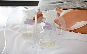 Close-up mother using automatic breast pump on the bed