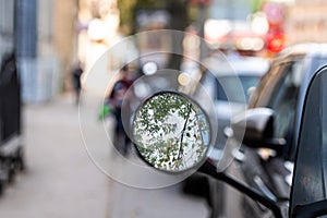 close-up of a motorcycle mirror parked on the side of the street  selective focus