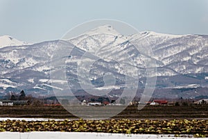 Close up Mount Yotei inactive stratovolcano with village on the foot hill and snow cover on the ground in winter in Hokkaido