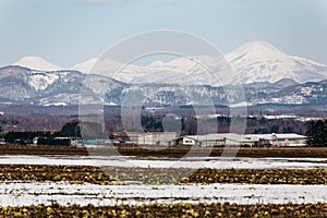 Close up Mount Yotei inactive stratovolcano with village on the foot hill and snow cover on the ground in winter in Hokkaido