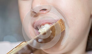 Close up of a mouth of a caucasian little child eating bread and honey