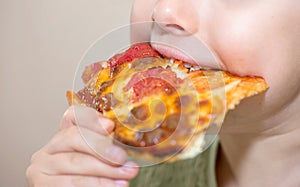 Close up of the mouth of a child eating a slice of pizza