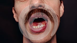 Close-up of the mouth of man who sings a song and speaks to the camera