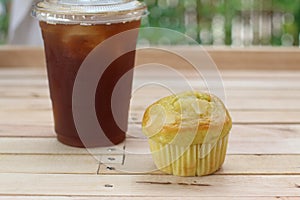 Close up muffin with iced coffee on wooden background.