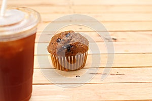 Close up muffin with iced coffee on wooden background.