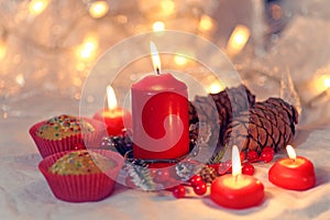 Close up of muffins in a red wrapper with red candles and holiday wreath. Bokeh background with a shallow depth of field.