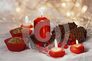 Close up of muffins in a red wrapper with red candles and holiday wreath. Bokeh background with a shallow depth of field.