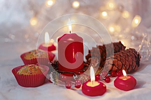 Close up of muffins in a red wrapper with red candles and holiday wreath. Bokeh background with a shallow depth of field.