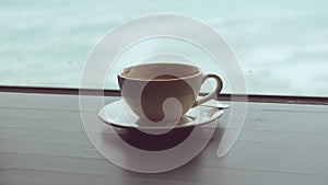 close-up of a mug with coffee on a table against the background of a window overlooking the stormy sea