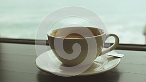 Close-up of a mug with coffee on a table against the background of a window overlooking the stormy sea