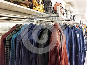 A close-up of a multi-colored hoodie jacket hanging neatly on a hanger in a retail clothing store