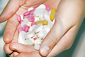 Close-up of multi-colored pills and capsules on the open palm of a painkiller pill