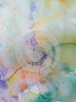 Close-up of multi-colored watercolor stains on paper. Yellow, green, blue, brown blots, drips, drops.