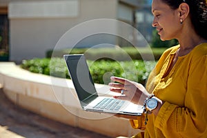 Close-up multi ethnic woman talking with business partners via video link, using a laptop with black blank mockup screen