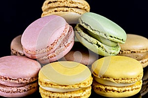 Close up multicolored macarons on black background