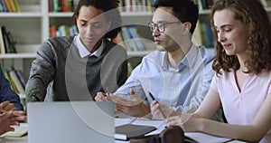 Close up multiethnic students work on joint task in library