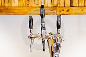 Close up of multiple beer taps located over a wooden table in a blurred background