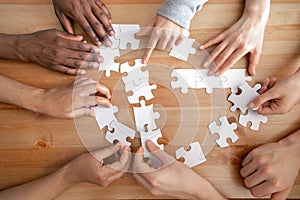 Close up multiracial people, team assembling puzzle, success teamwork