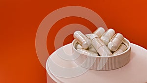 Close-up of multivitamin biologically active supplements on orange background. mental wellbeing and personal health concept