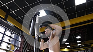 Close-up of muscular man with a bare torso training on a rotating boxing machine