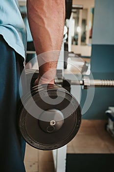 Close-up of a muscular young man lifting weights in gym