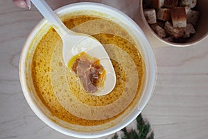 Close-up of mushroom soup in a paper glass. Takeaway food in the restaurant. The concept of vegetarian fast food in the meal