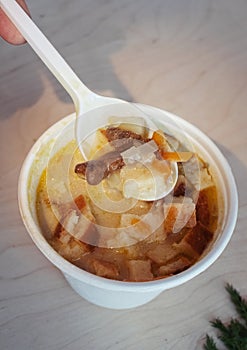 Close-up of mushroom soup in a paper glass. Takeaway food in the restaurant. The concept of vegetarian fast food in the meal