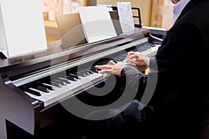 Close-up of a music performer`s hand playing the piano. Side view of instrument musical tool. Close up to the piano keyboard