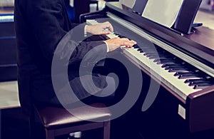 Close-up of a music performer`s hand playing the piano. Side view of instrument musical tool. Close up to the piano keyboard