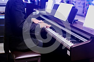 Close-up of a music performer`s hand playing the piano. Side view of instrument musical tool. Close up to the piano keyboard